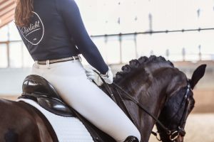 Dressurreiterin Victoria Wurzinger auf ihrem Pferd mit Reithelm und Tierlicht Poloshirt