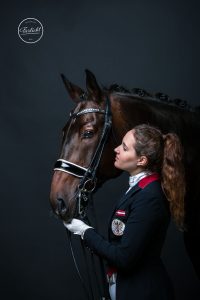 Dressurreiterin Victoria Wurzinger mit Pferd in einem Frack vor schwarzem Hintergrund