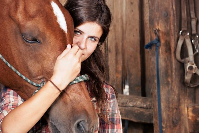 Mädchen mit einem braunen Pferd im Reitstall