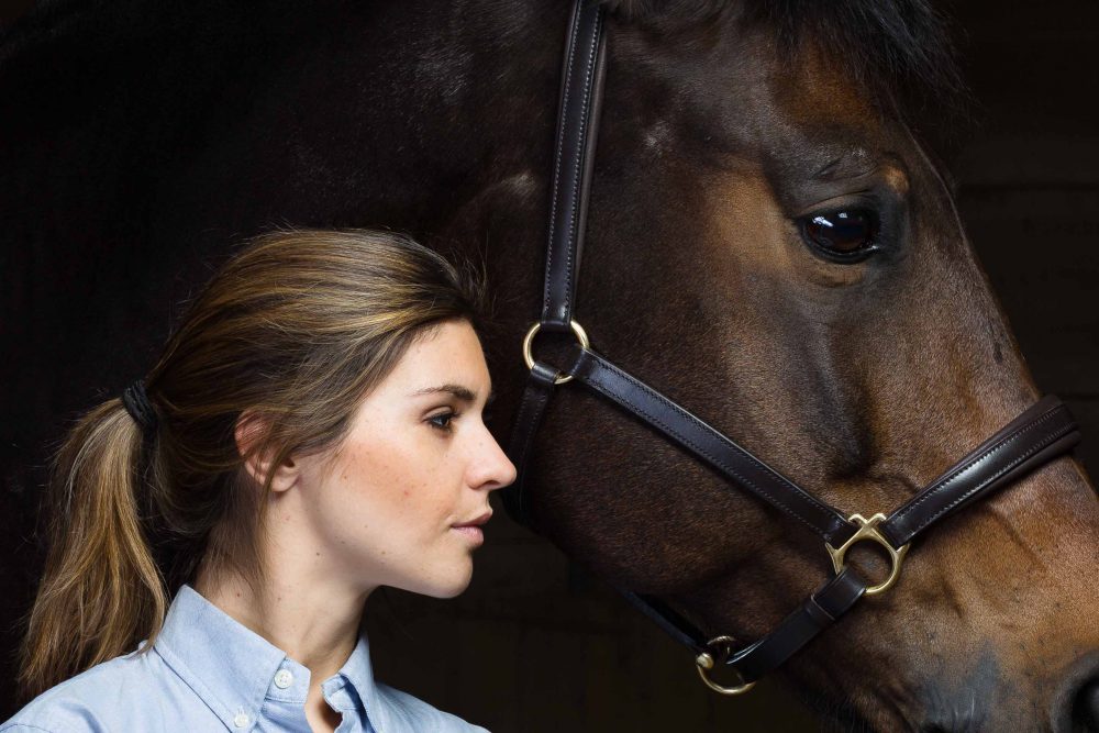 Frau mit braunem Pferd vor schwarzem Fotohintergrund